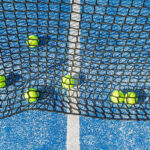 Yellow Balls on a Blue Court Seen from Behind the net